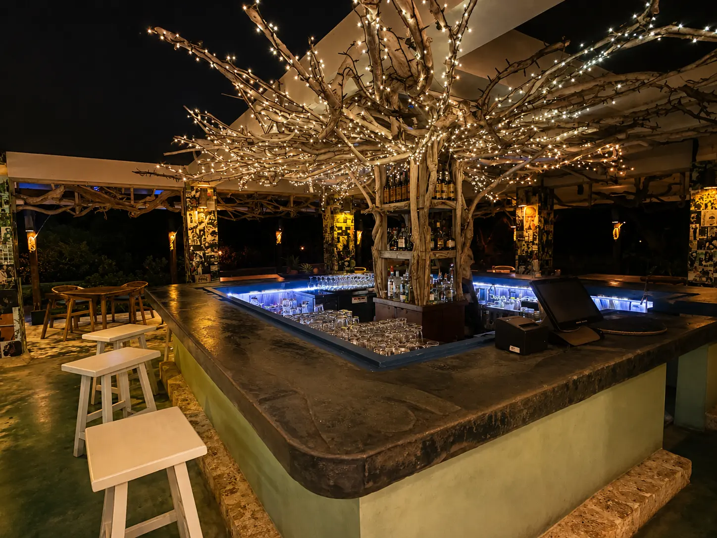 Shabeen Bar at GoldenEye Jamaica at night, with its central tree bar illuminated by string lights.