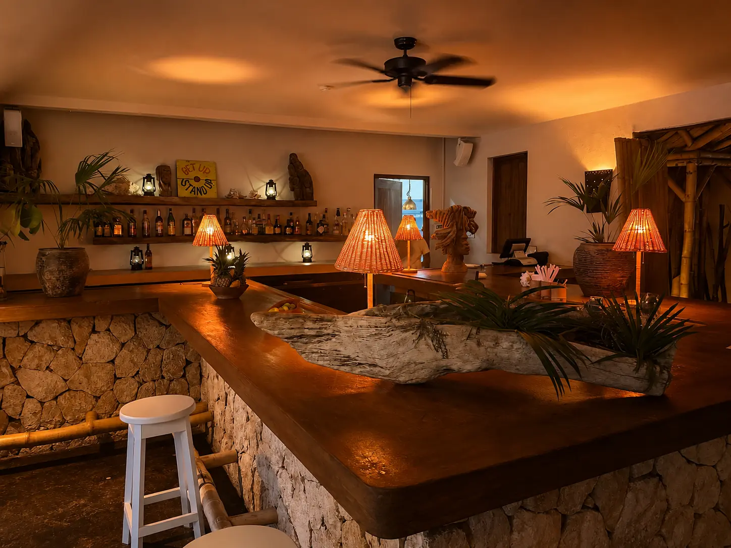 Bar inside The Gazebo restaurant at GoldenEye Jamaica, with timber counters, stonework and warm evening lighting.