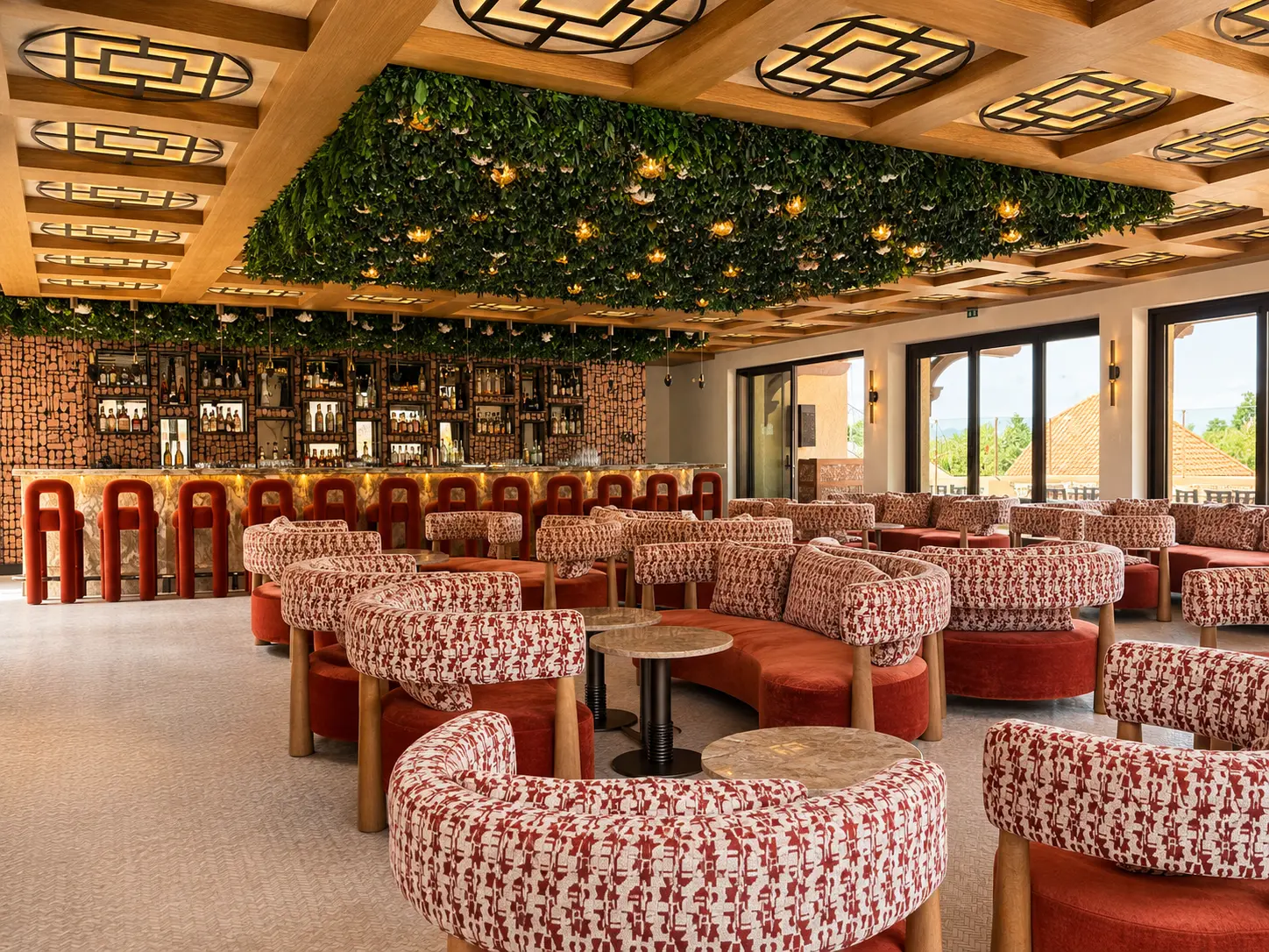 B. Lounge at Byblos Saint-Tropez with patterned red seating and ceiling greenery