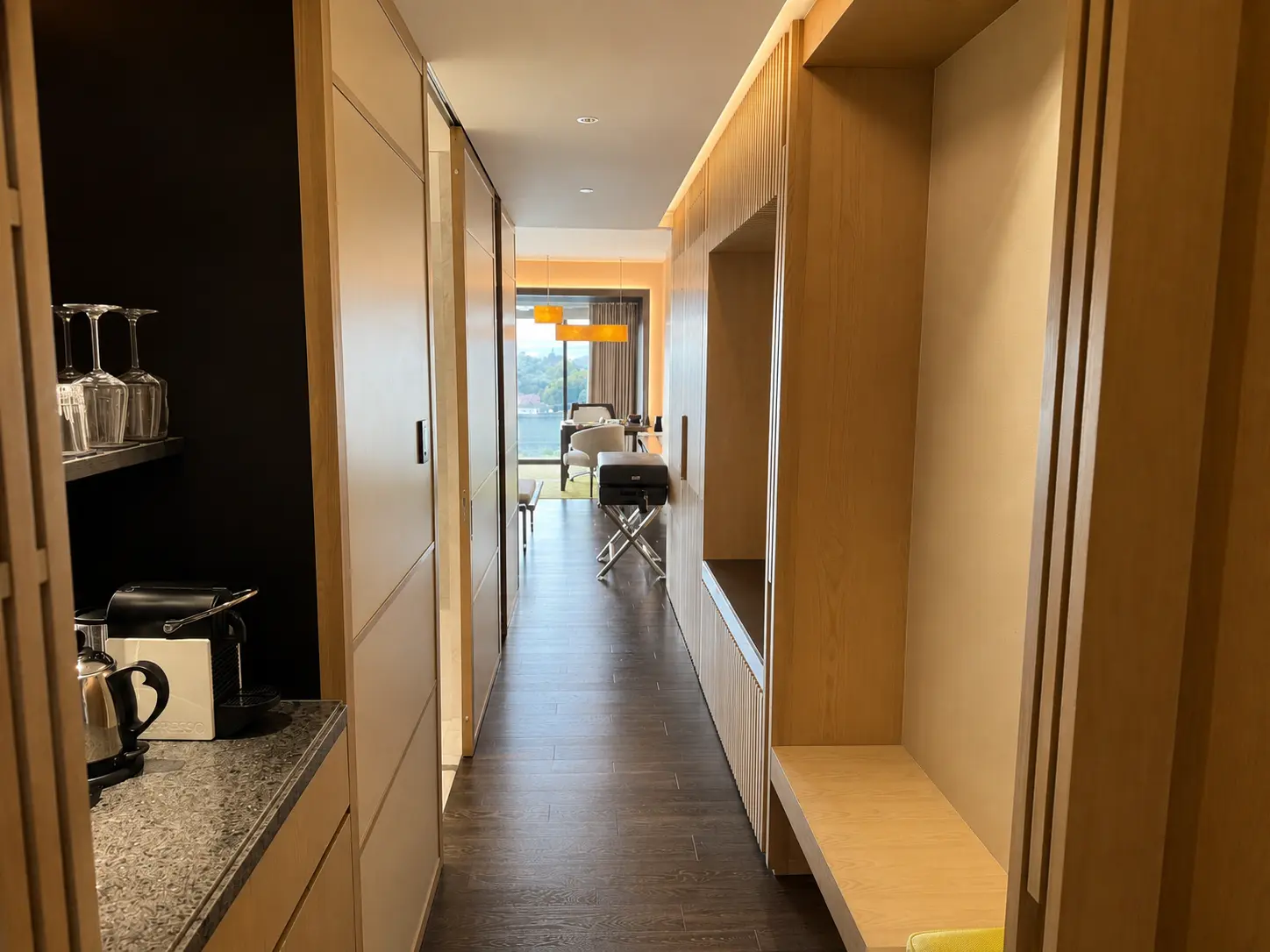 Entry hallway inside a guest room at Four Seasons Hotel Kyoto with timber cabinetry, luggage bench and coffee station.
