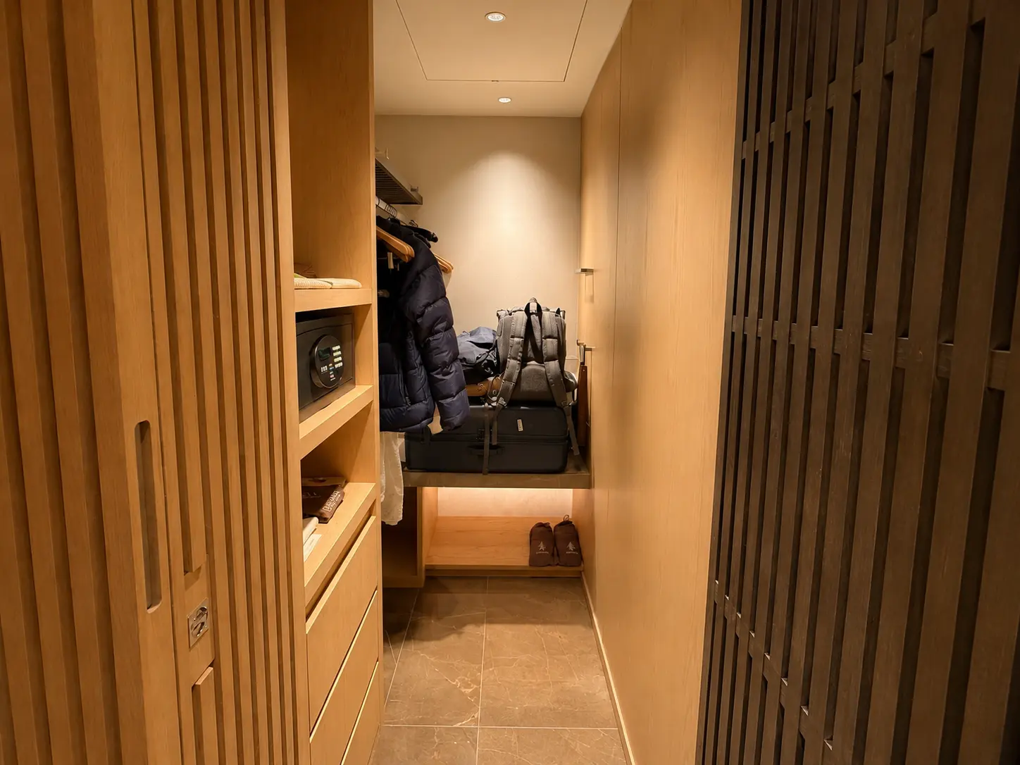 Walk-in closet in a Deluxe Room at Four Seasons Hotel Kyoto with built-in timber storage, safe and luggage space.