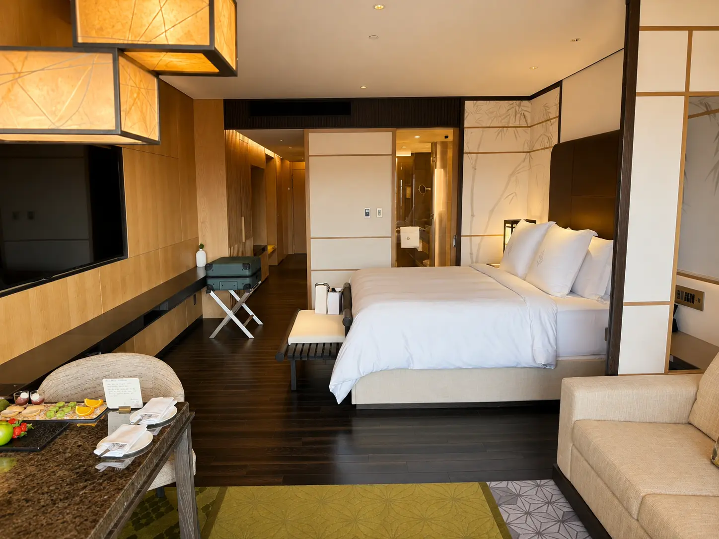 Deluxe Room at Four Seasons Hotel Kyoto with king bed, sofa, Japanese-inspired wall panels and Preferred Partner welcome amenity.