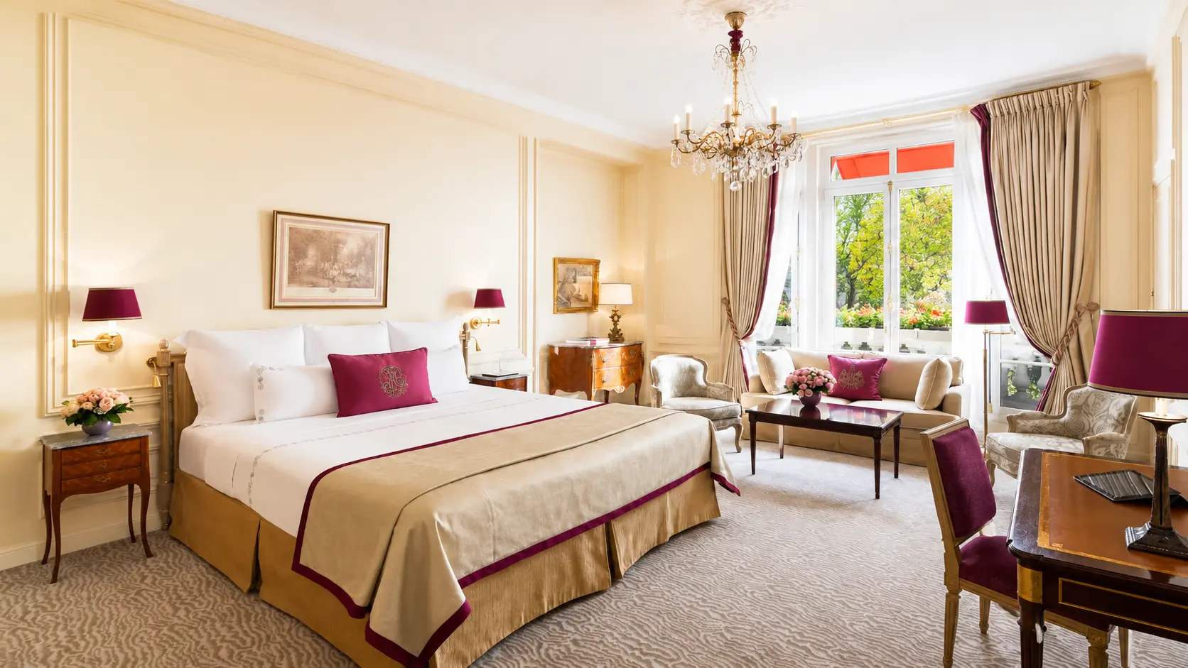 Classic Deluxe Room at Hôtel Plaza Athénée Paris with king bed, chandelier, sitting area and signature red awnings.