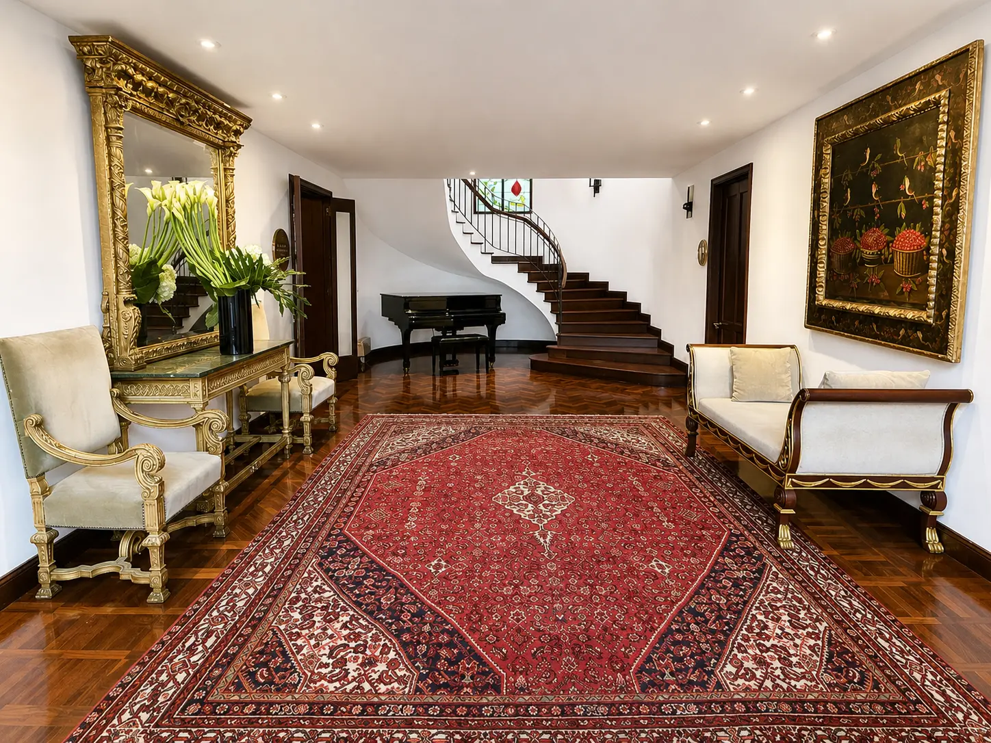 Lobby at Four Seasons Hotel Casa Medina Bogotá with grand piano, sweeping staircase, Persian rug and antique-style furnishings.
