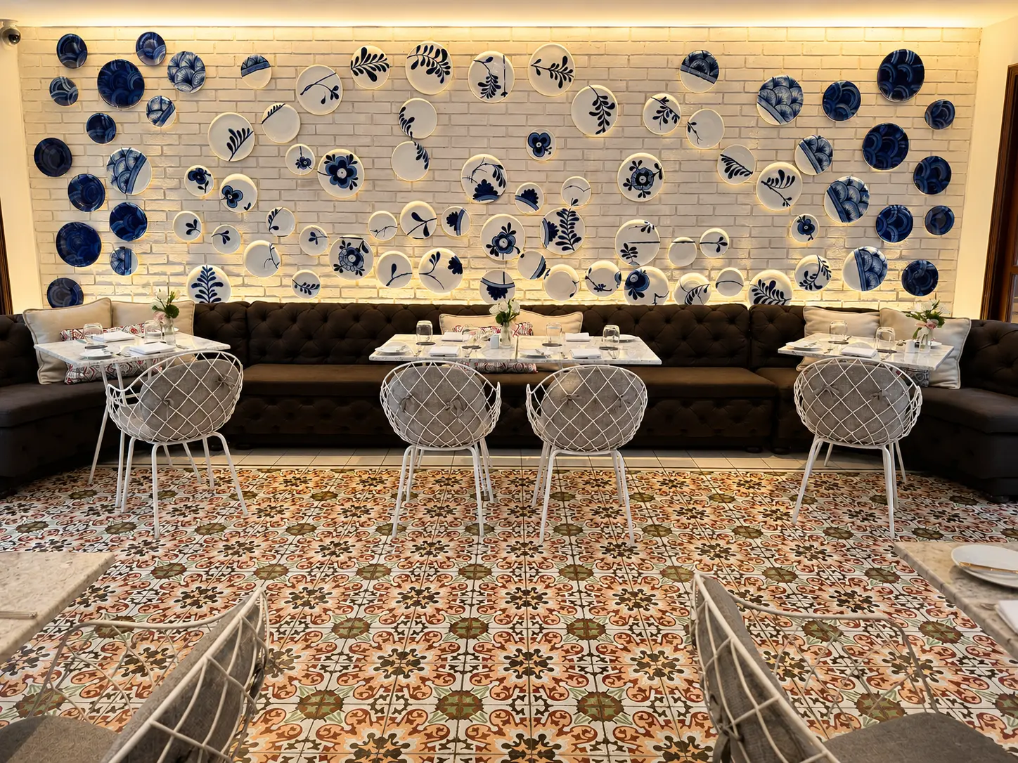 Castanyoles restaurant at Four Seasons Hotel Casa Medina Bogotá with patterned tile floors, banquette seating and blue-and-white ceramic wall art. 