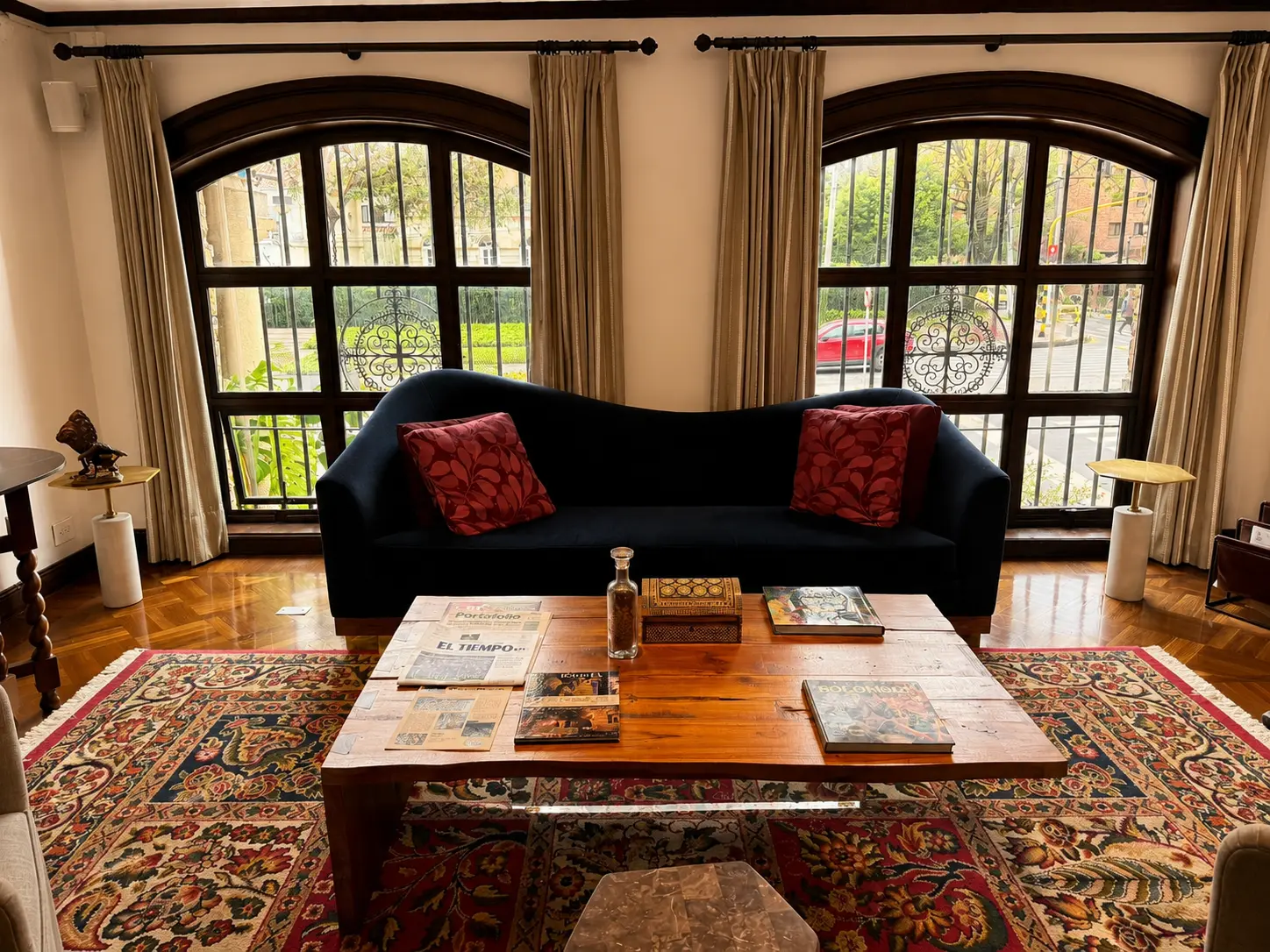 Lounge at Four Seasons Hotel Casa Medina Bogotá with arched windows, dark sofa, Persian rug and coffee table. 