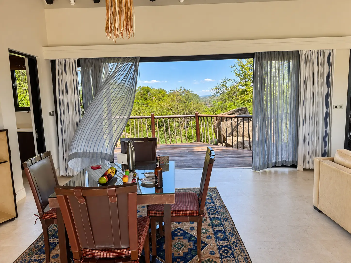 Dining area in a One-Bedroom Villa at Four Seasons Safari Lodge Serengeti, with open doors leading to a private terrace overlooking the Serengeti.