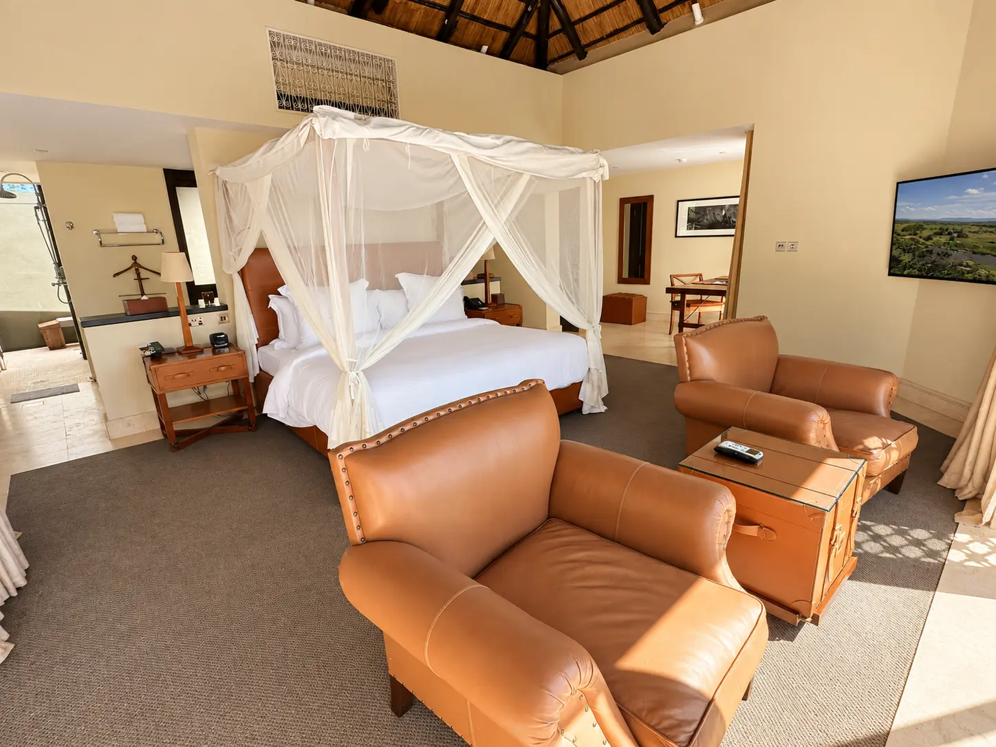 King bedroom with mosquito-net canopy and sitting area in a One-Bedroom Villa at Four Seasons Safari Lodge Serengeti, Tanzania.