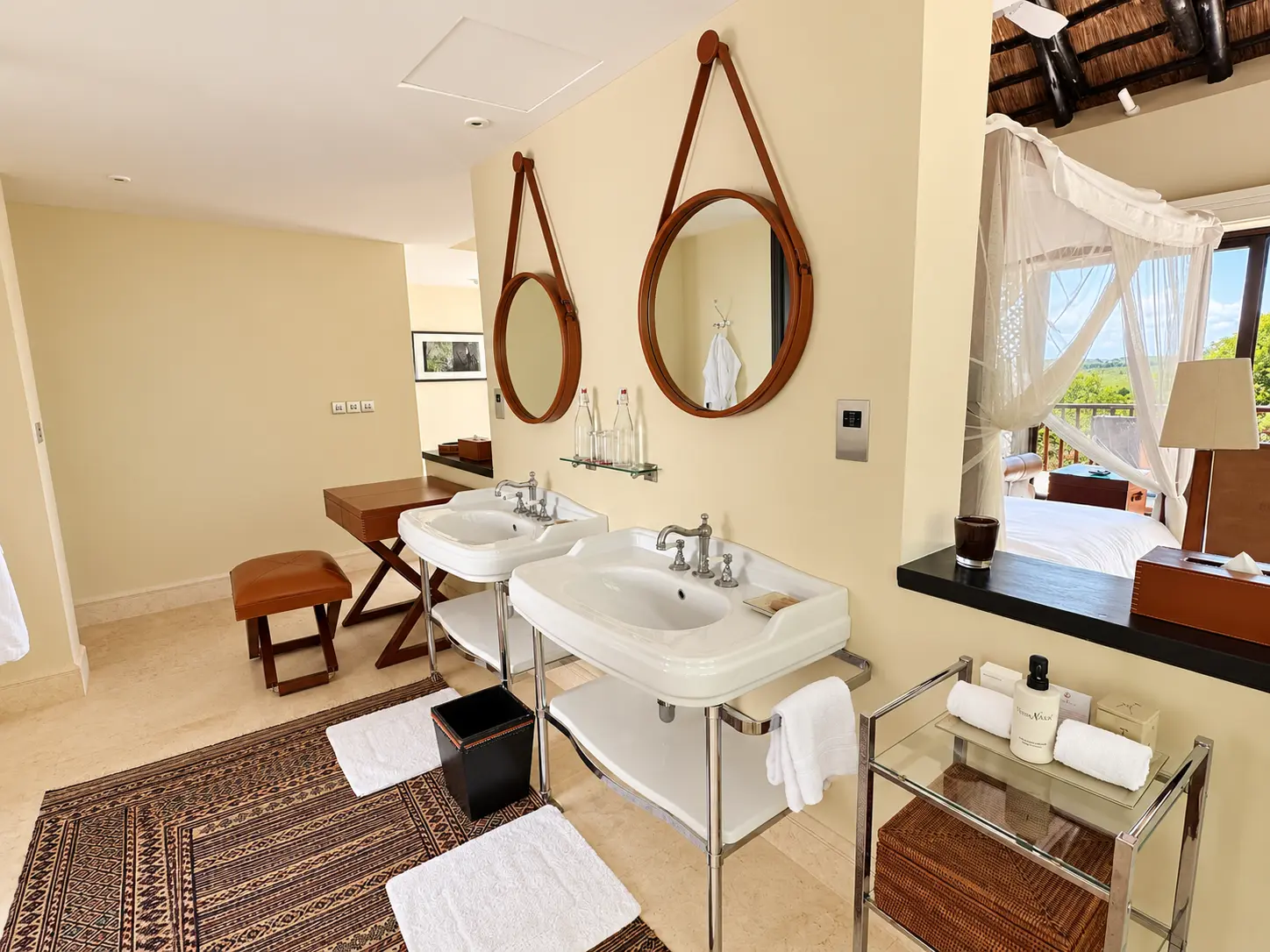 Bathroom with double vanity and open bedroom in a One-Bedroom Villa at Four Seasons Safari Lodge Serengeti, Tanzania.