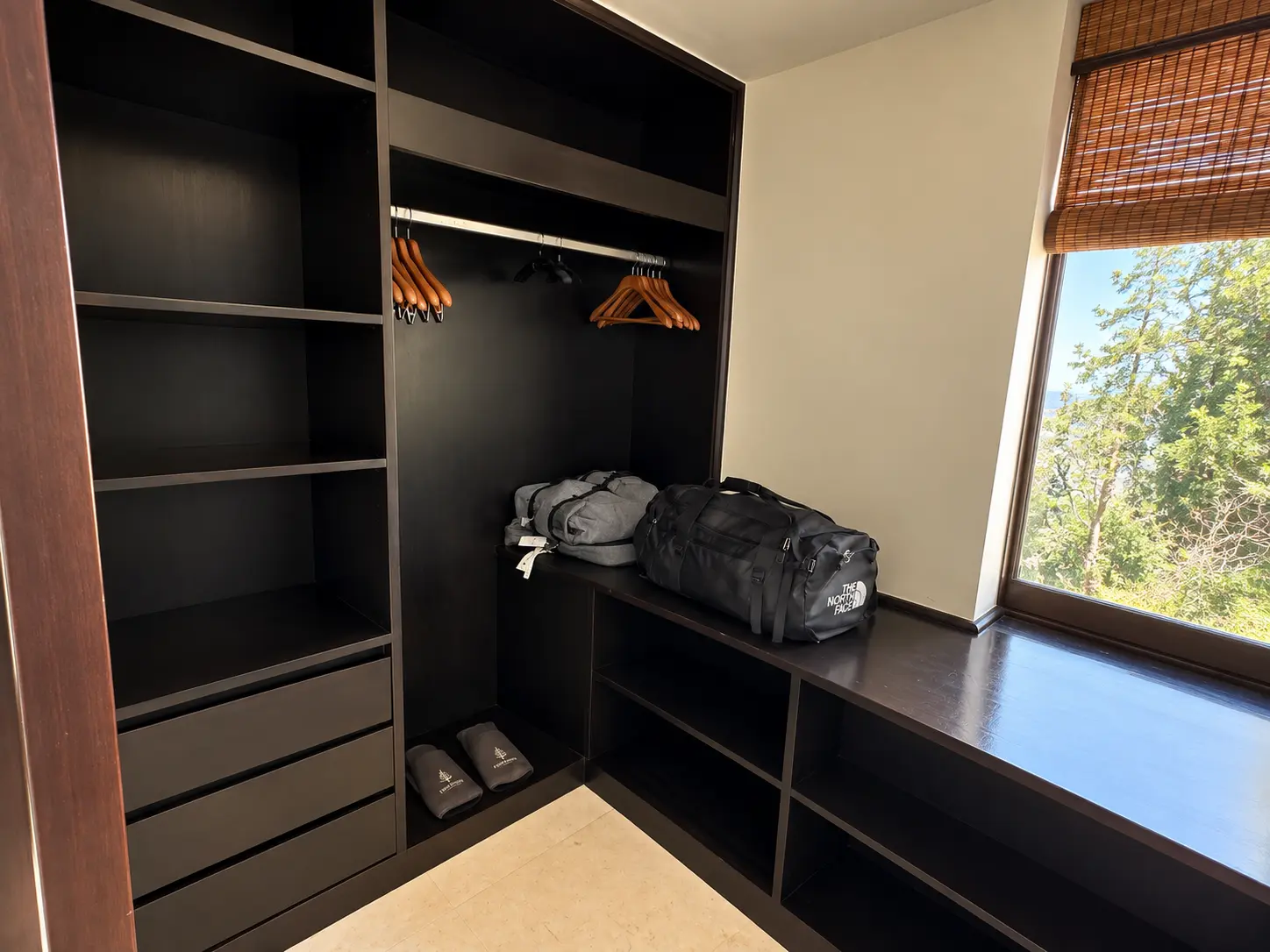 Walk-in closet with dark wood storage and luggage at Four Seasons Safari Lodge Serengeti in Tanzania.