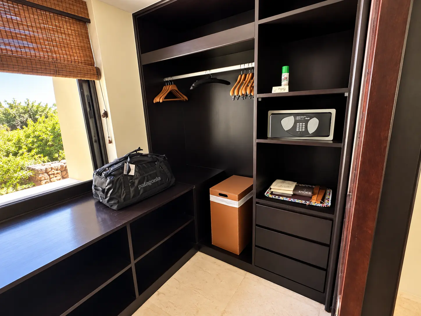 Walk-in closet with luggage storage, wooden hangers and in-room safe at Four Seasons Safari Lodge Serengeti in Tanzania.