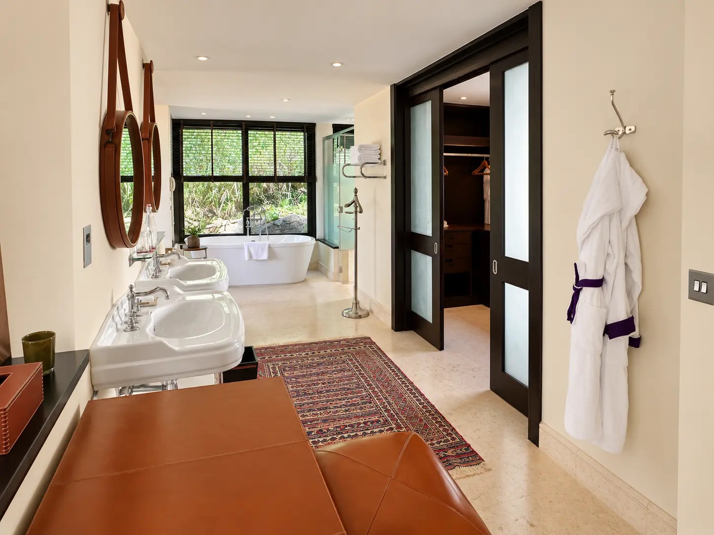 Large bathroom with double sinks, freestanding bathtub and walk-in closet in a One-Bedroom Villa at Four Seasons Safari Lodge Serengeti.