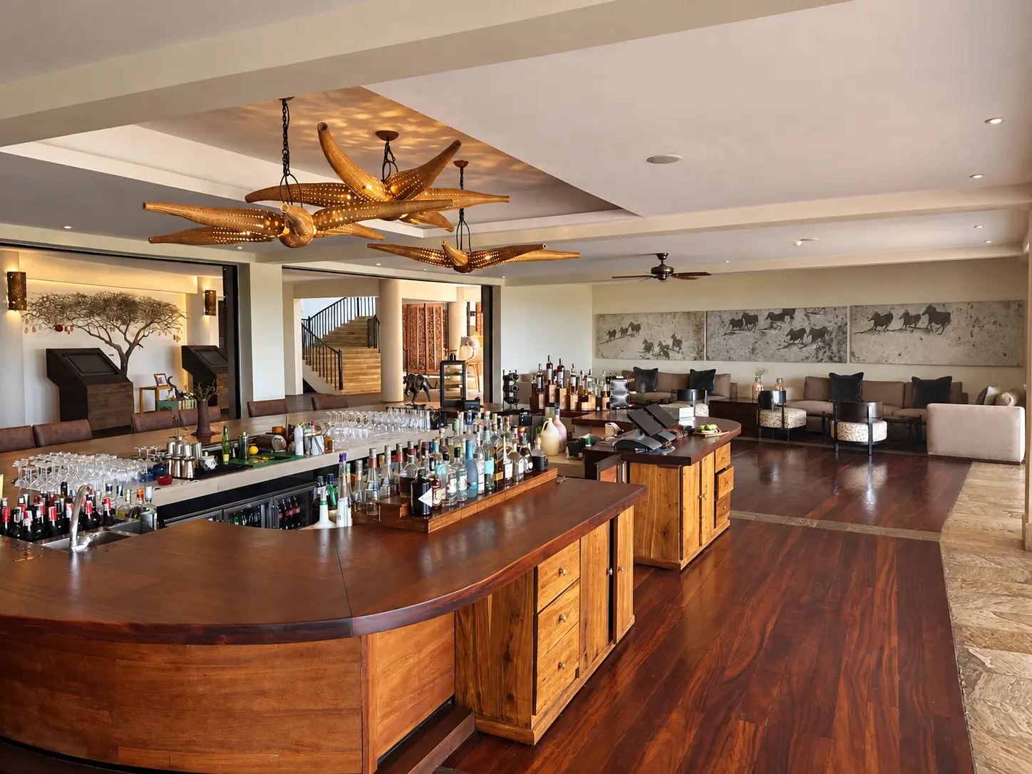 Maji Bar at Four Seasons Safari Lodge Serengeti with a large wooden bar and lounge overlooking the Serengeti.