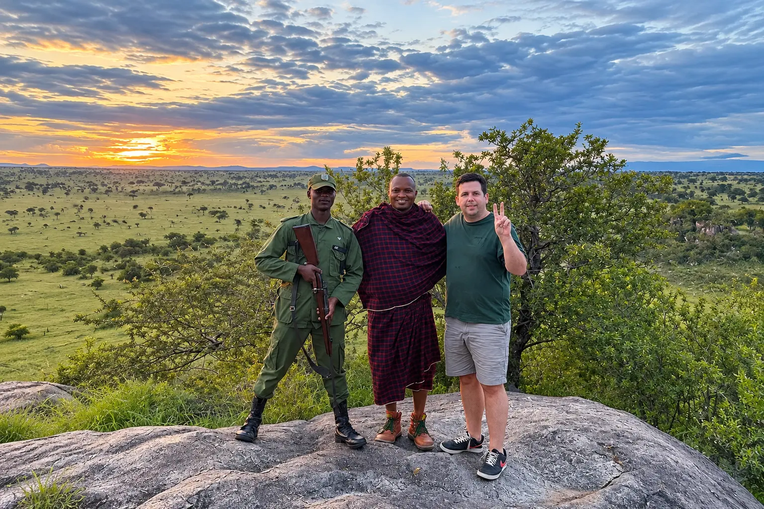 Four Seasons Safari Lodge Serengeti staff with a guest overlooking the Serengeti at sunset.