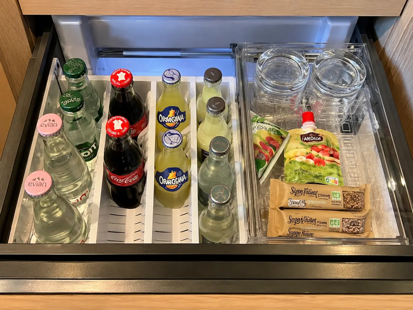 Minibar drawer at Aman Le Mélézin with water, soft drinks, juices and snacks.