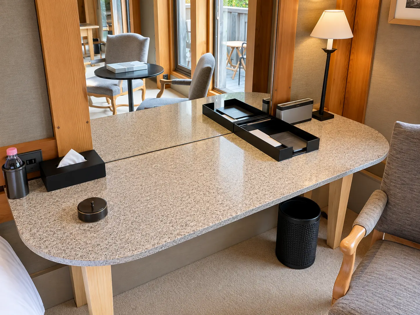 Large desk and dressing area in a Chambre Ski Piste at Aman Le Mélézin with a mirror, chair and balcony beyond.