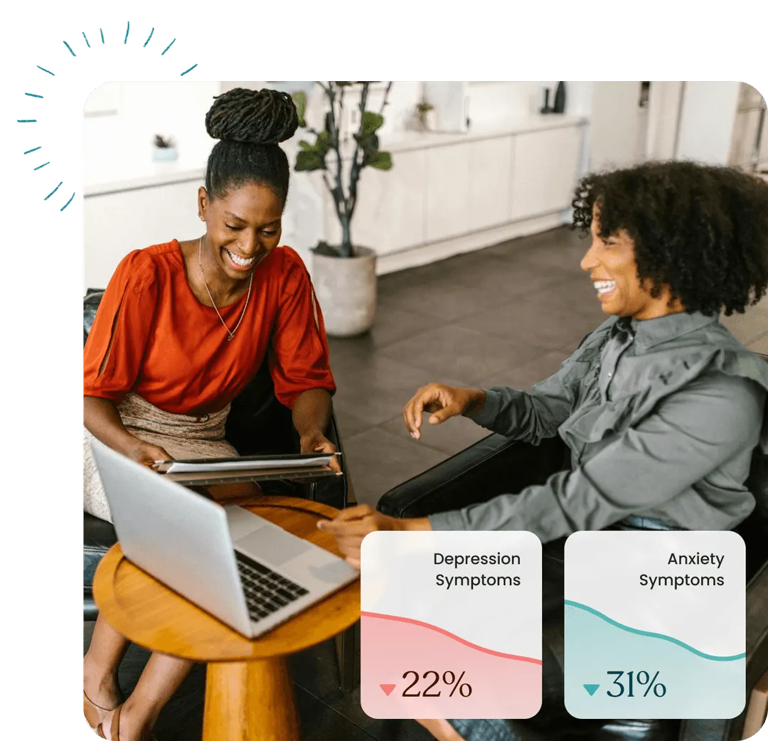 A couple of women sitting at a table with laptops.