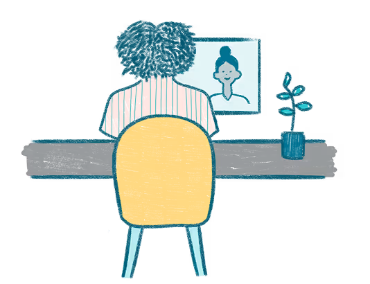 A woman sitting at a table with a potted plant in front of her.