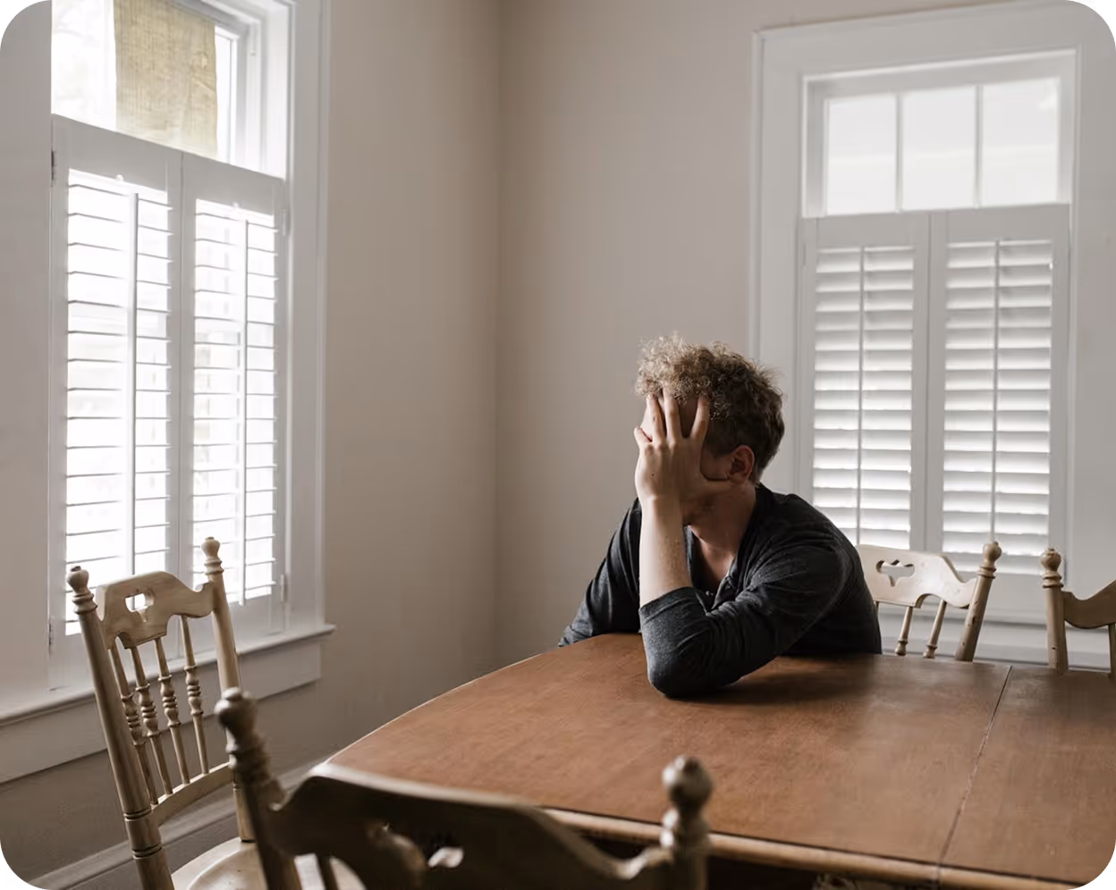 A man sitting at a wooden table in front of a window.