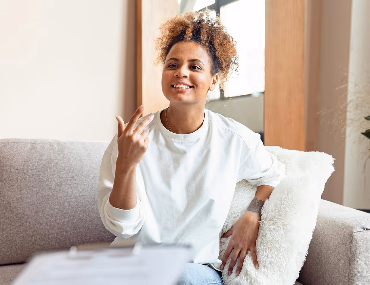 A woman sitting on top of a couch talking on a cell phone.