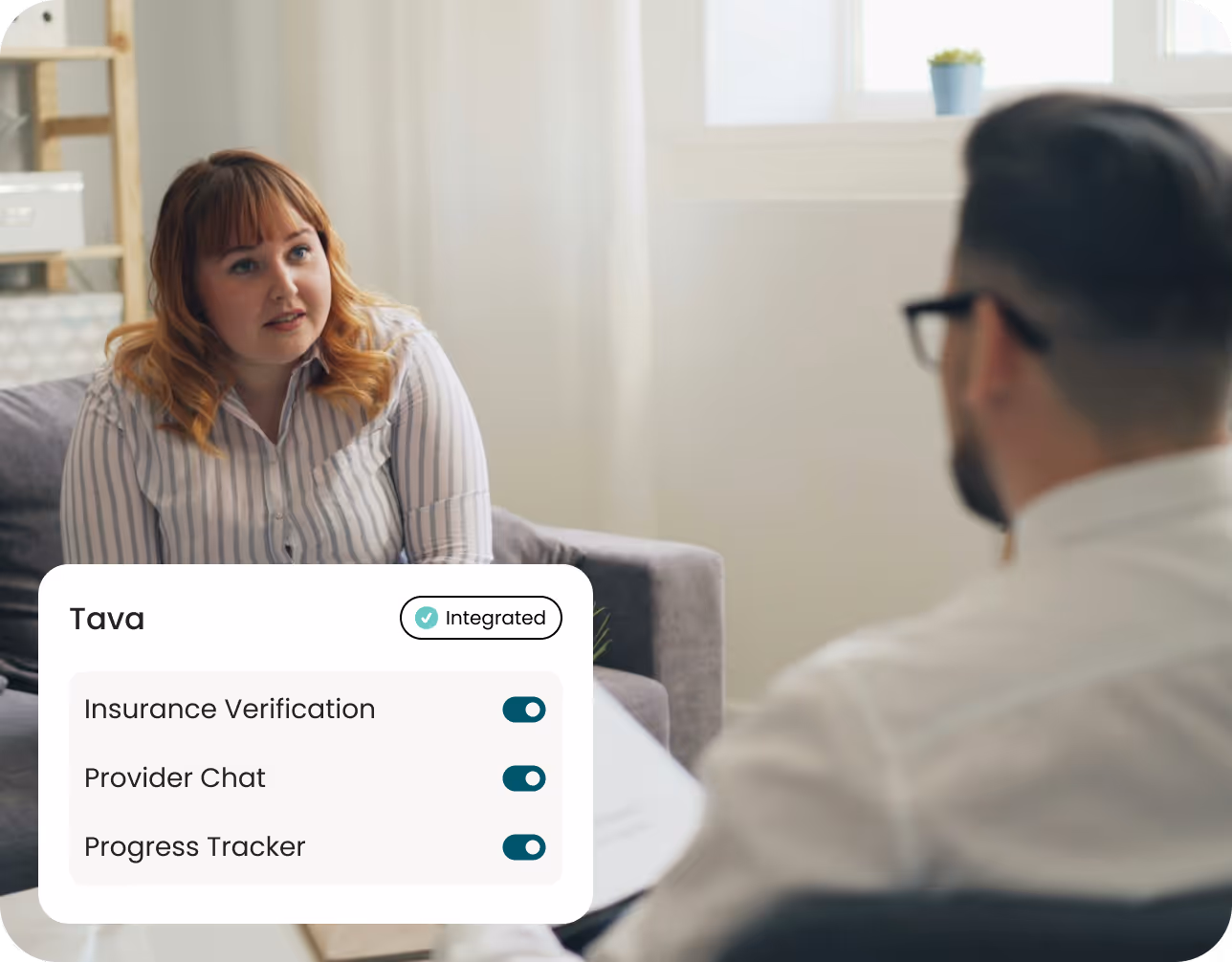 A woman talking to a man sitting on a couch.