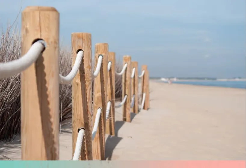 Wooden fence posts and rope along a beach