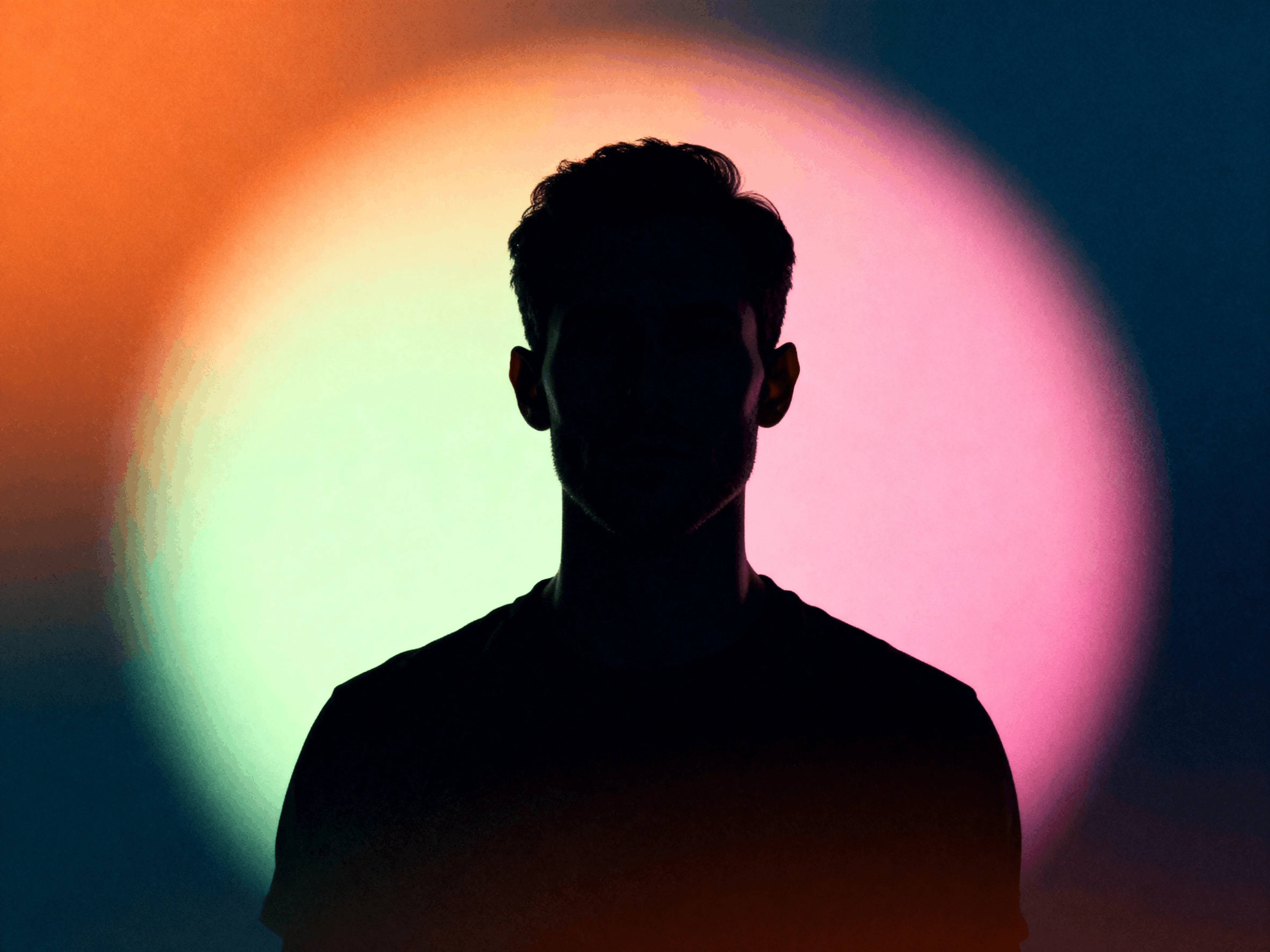 Silhouette of a man against a colorful circular gradient background with shades of pink, orange, and blue.