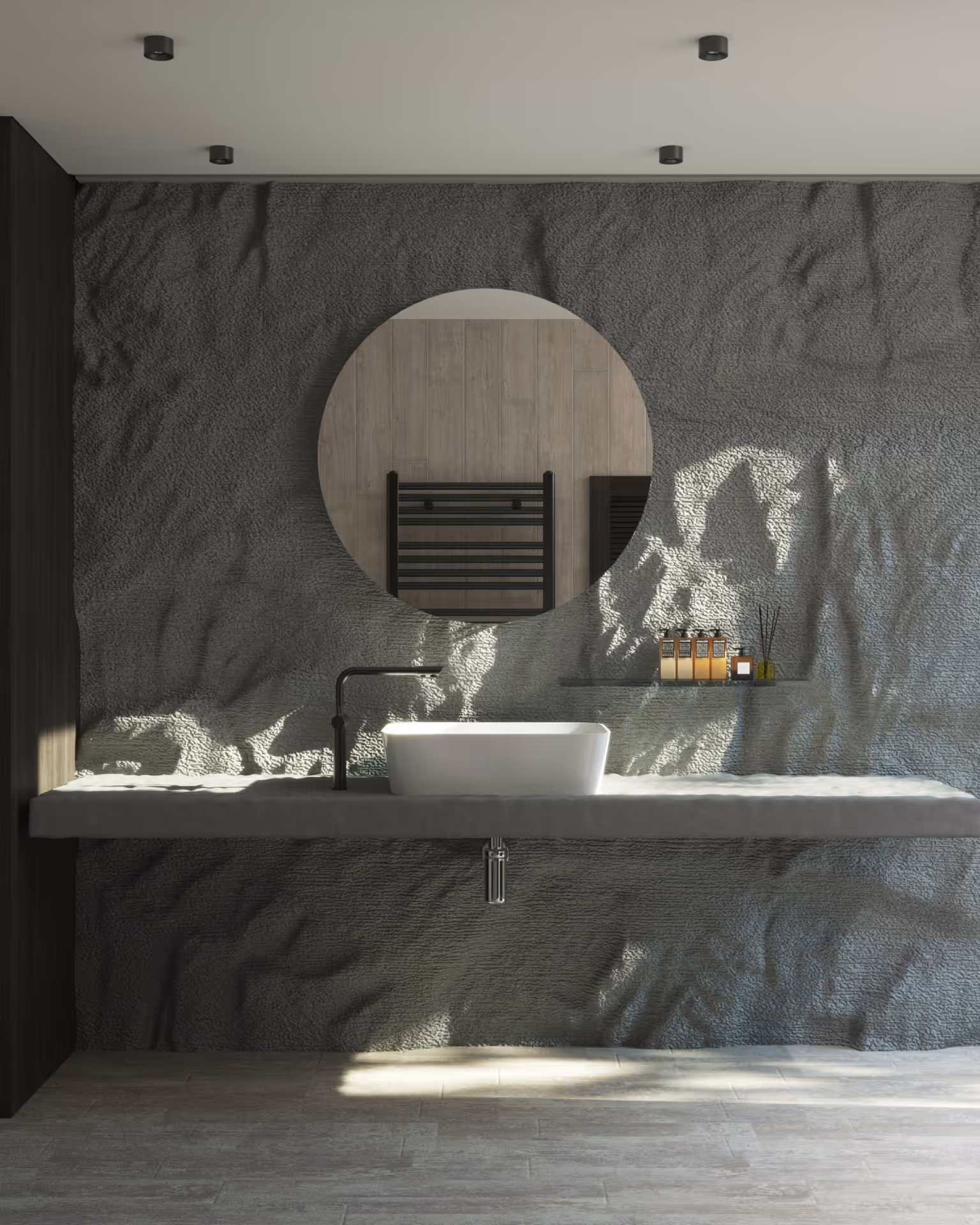 Modern bathroom sink with a round mirror on textured dark gray wall and wooden floor.