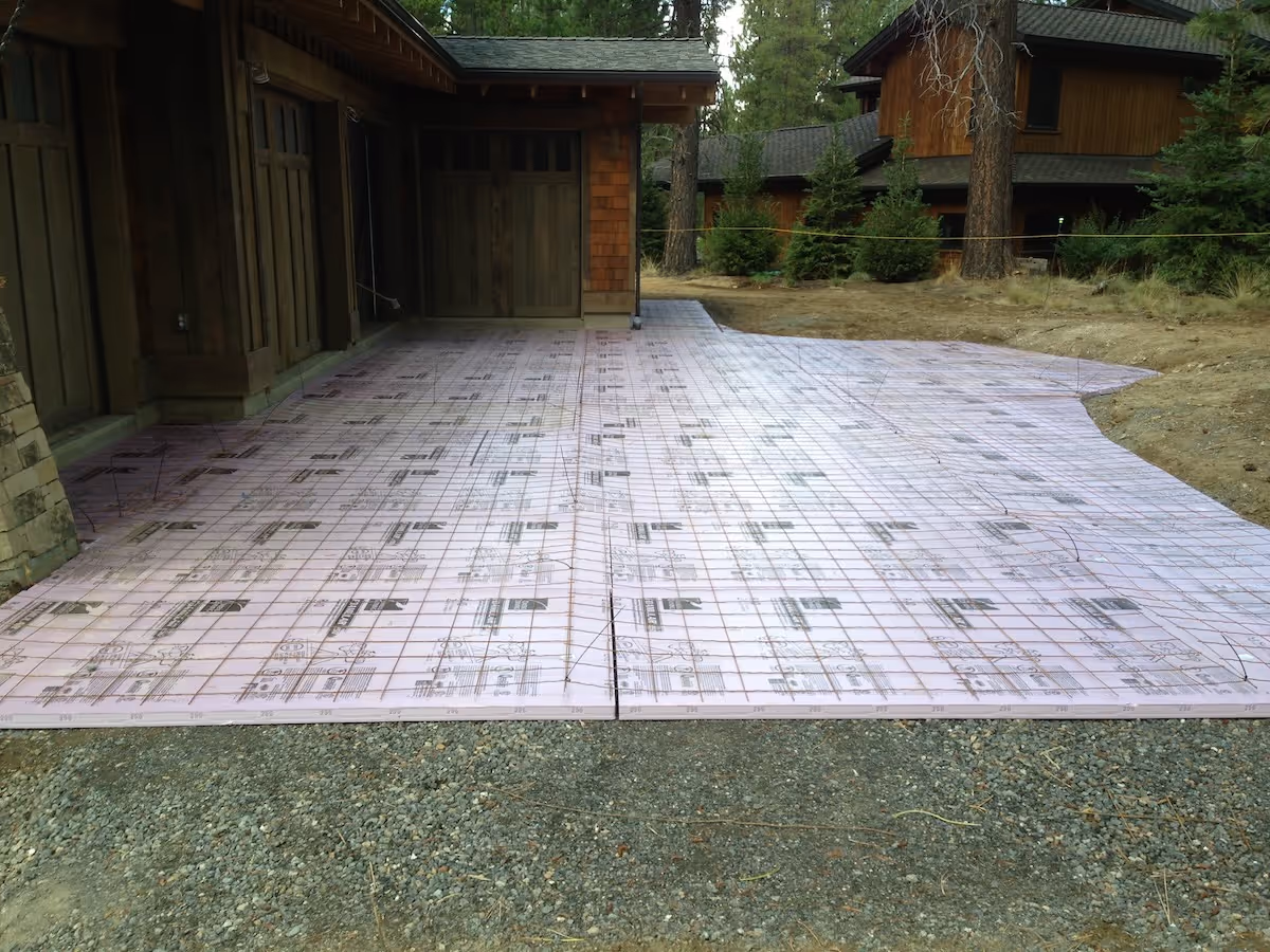 Outdoor area with wooden house walls and pink foam insulation boards laid for concrete pouring.