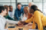 Team members placing their hands together over a table during a meeting