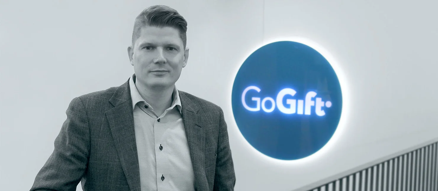 Portrait of a GoGift team member standing beside the illuminated GoGift logo