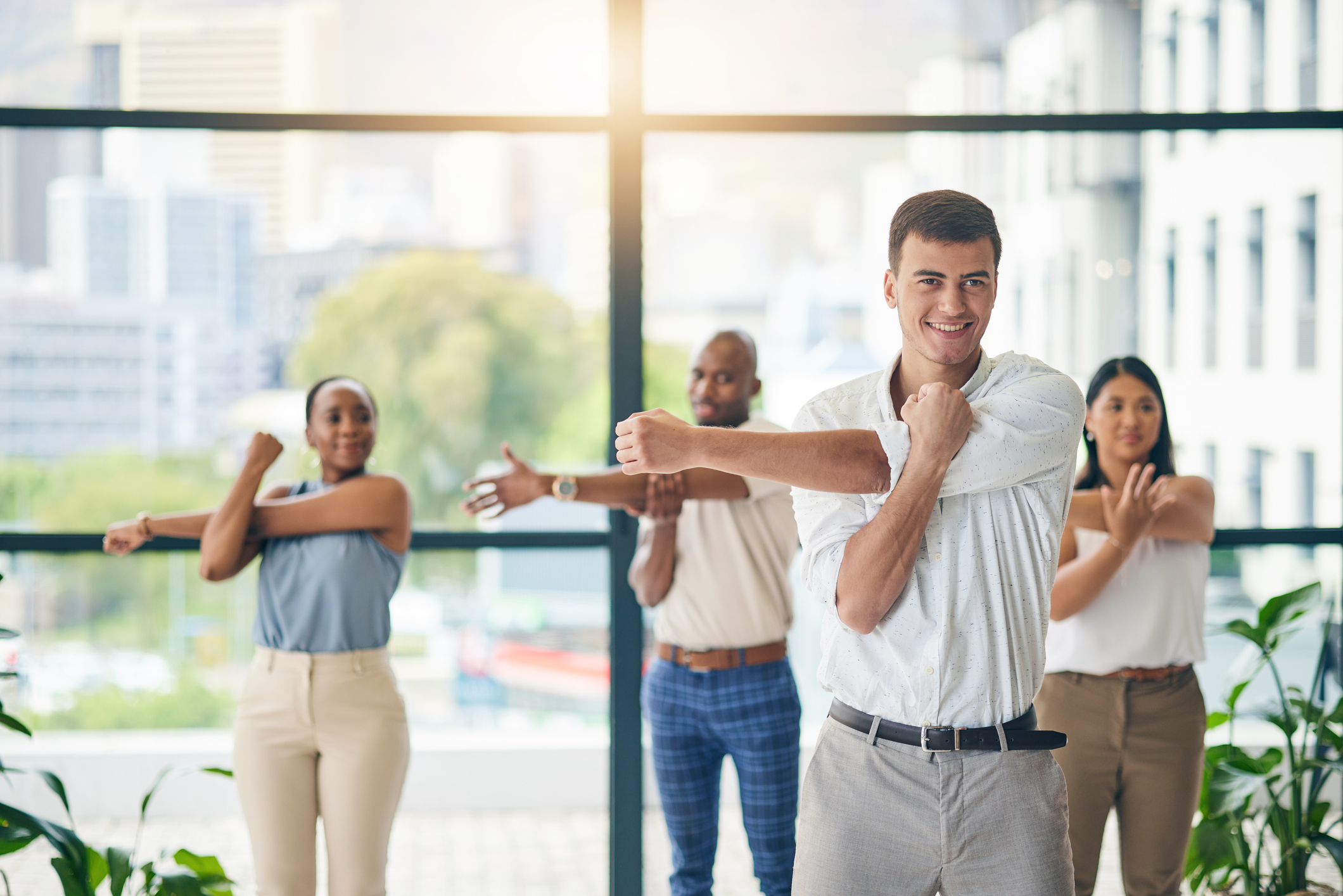 Office workers doing elbow bumps in a light-filled modern workspace.