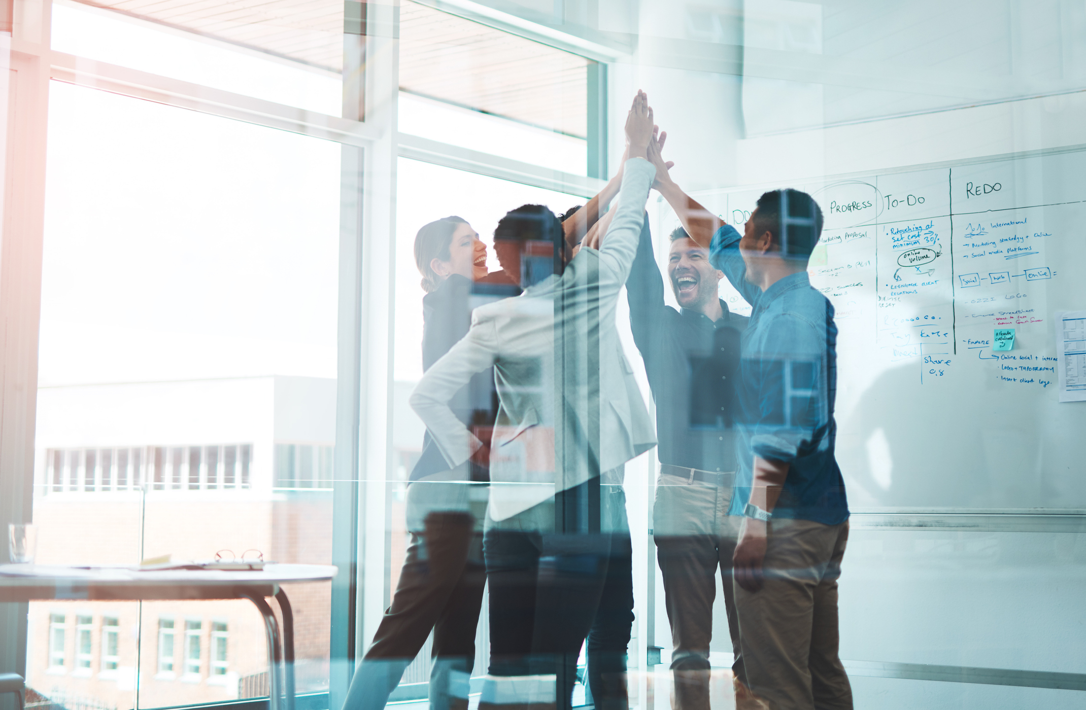 Team high-fiving in a sunny office