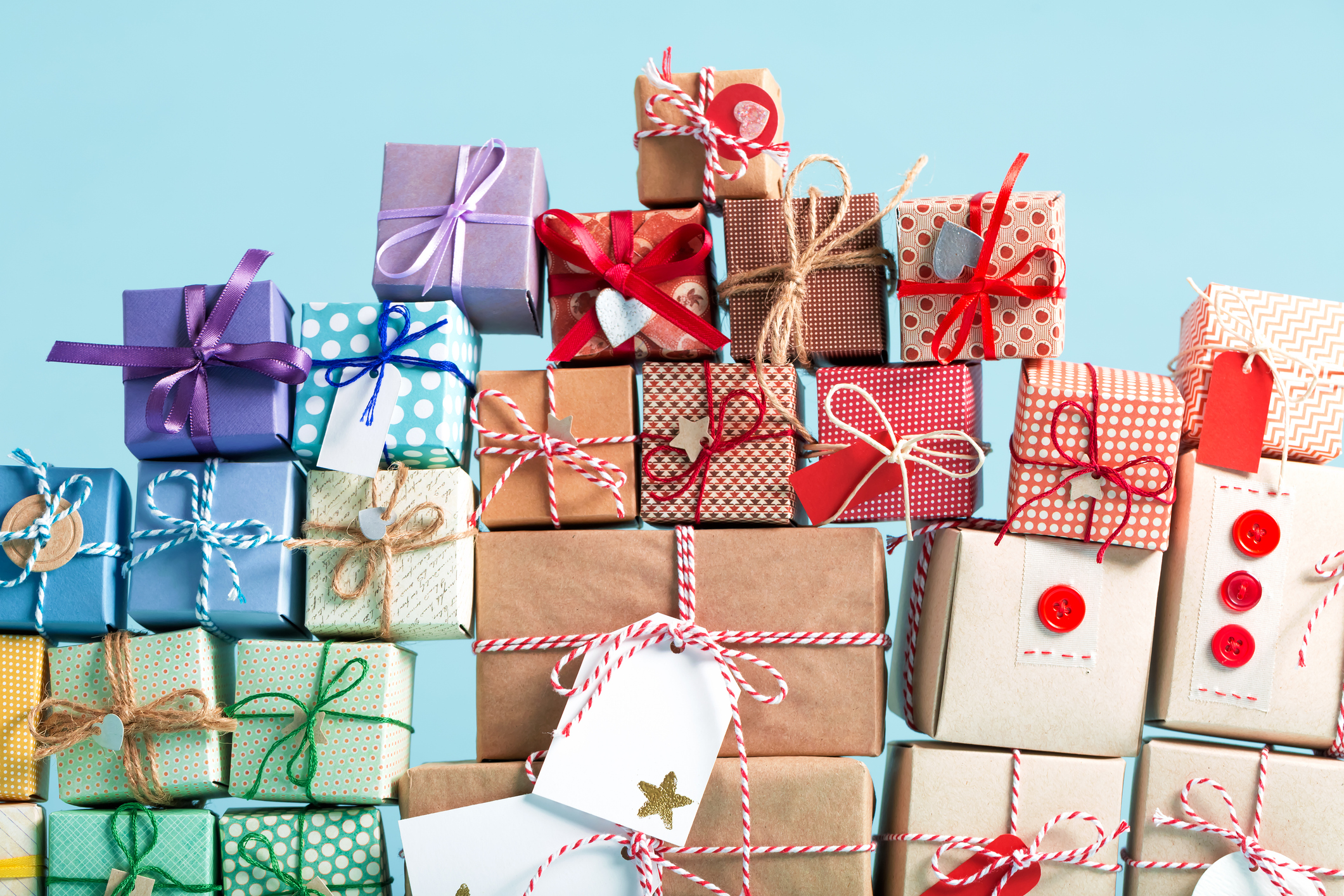 A collection of vibrant gift boxes with decorative ribbons stacked on a light blue background.