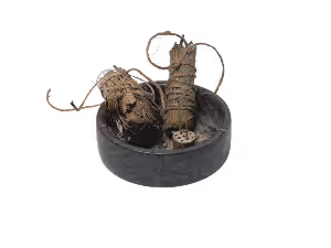 Two bundles of dried sage wrapped with string placed inside a round black container.