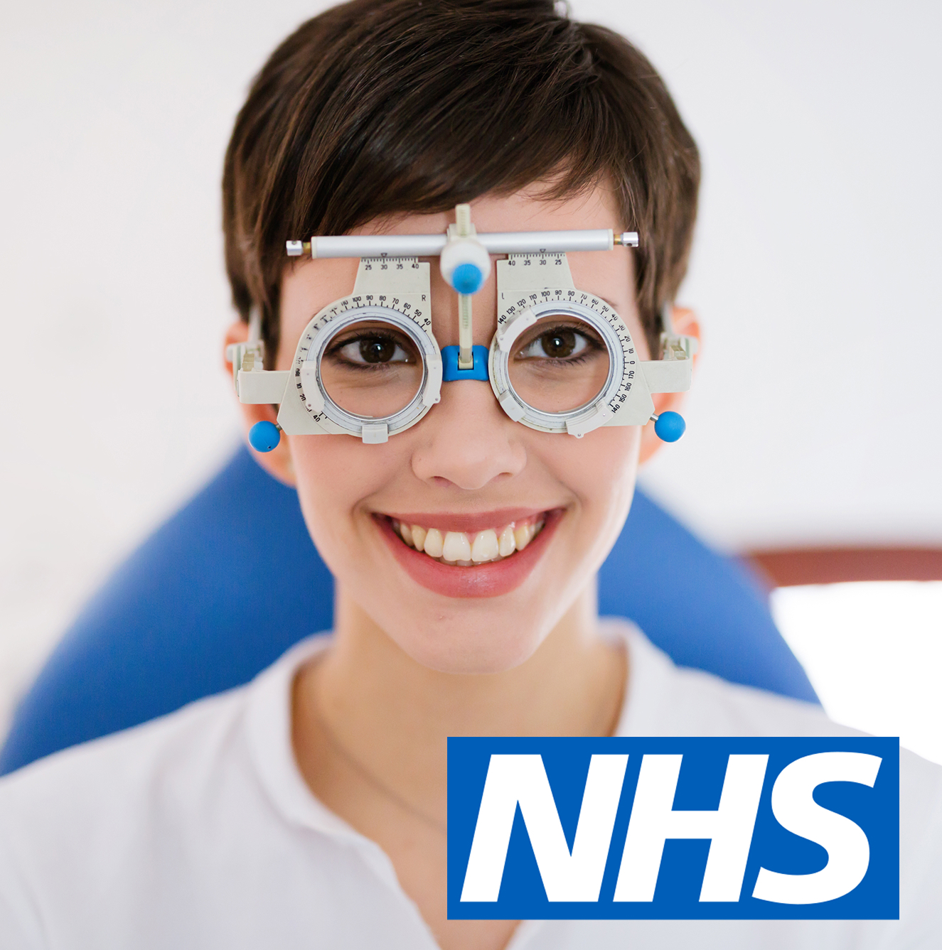 Smiling person wearing trial frame glasses for eye examination with NHS logo in corner