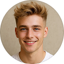 Young man with light brown hair smiling, wearing a white shirt against a beige background.