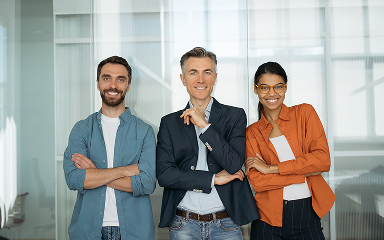 Three confident professionals standing with arms crossed in a modern office setting.