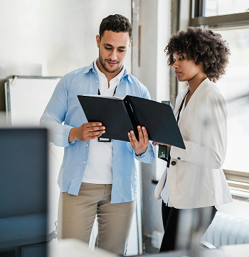 Two colleagues reviewing documents together in a modern office setting.