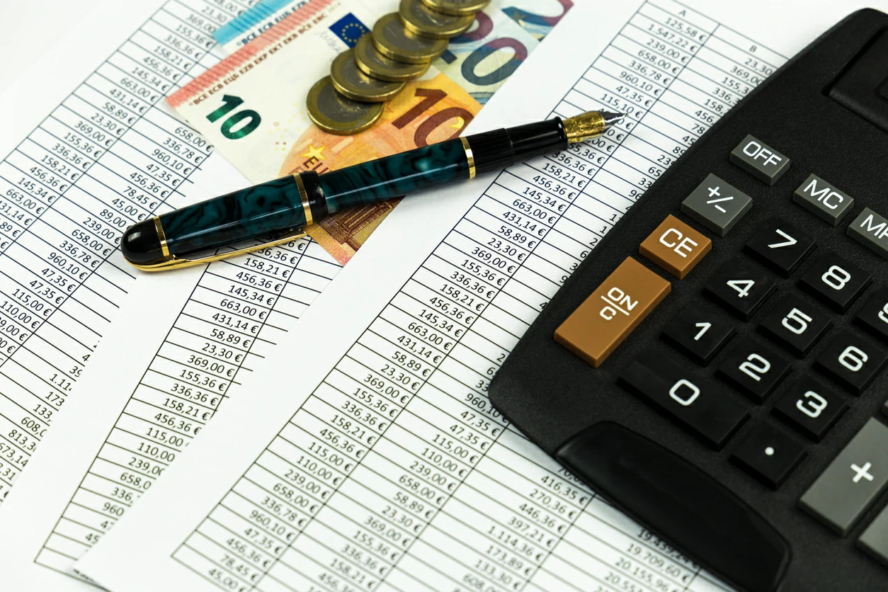 Document financier, billets et pièces en euro et une calculatrice.