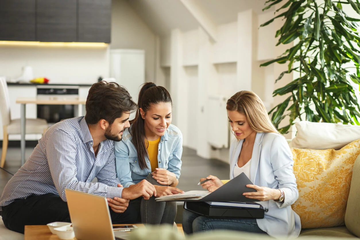 Un couple consultant des documents avec une professionnelle immobilier.