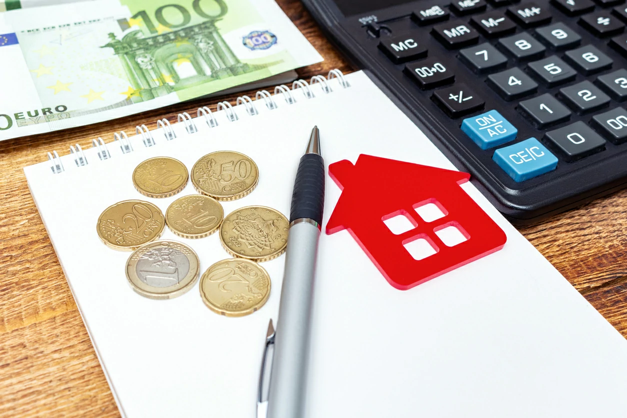Bloc-notes, stylo, carte en forme de maison, billet de 100 euros et une calculatrice.