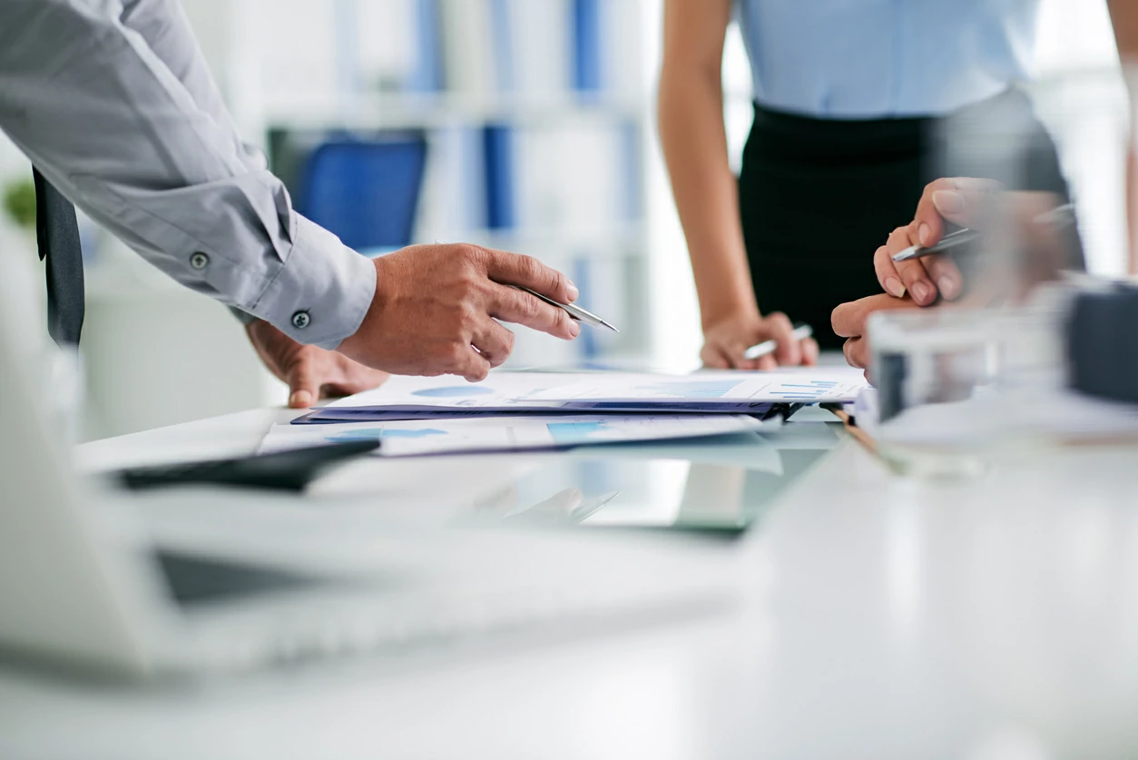 Trois personnes qui consultent des documents avec stylo à la main..