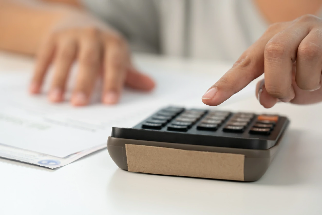 Main qui manipule une calculatrice à côté d'un document.