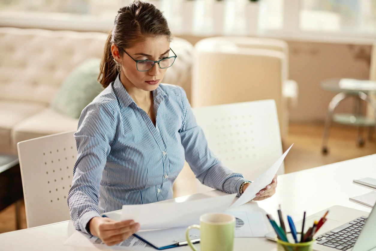 Femme avec un air concentré lisant des documents.