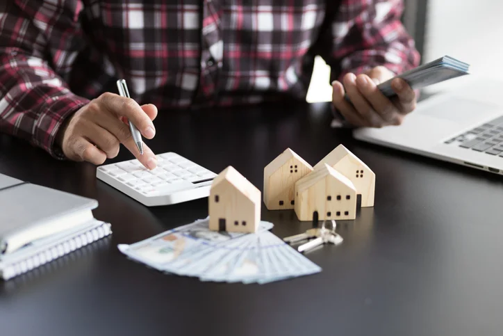 Homme utilisant une calculatrice et tenant des liasses de billet.