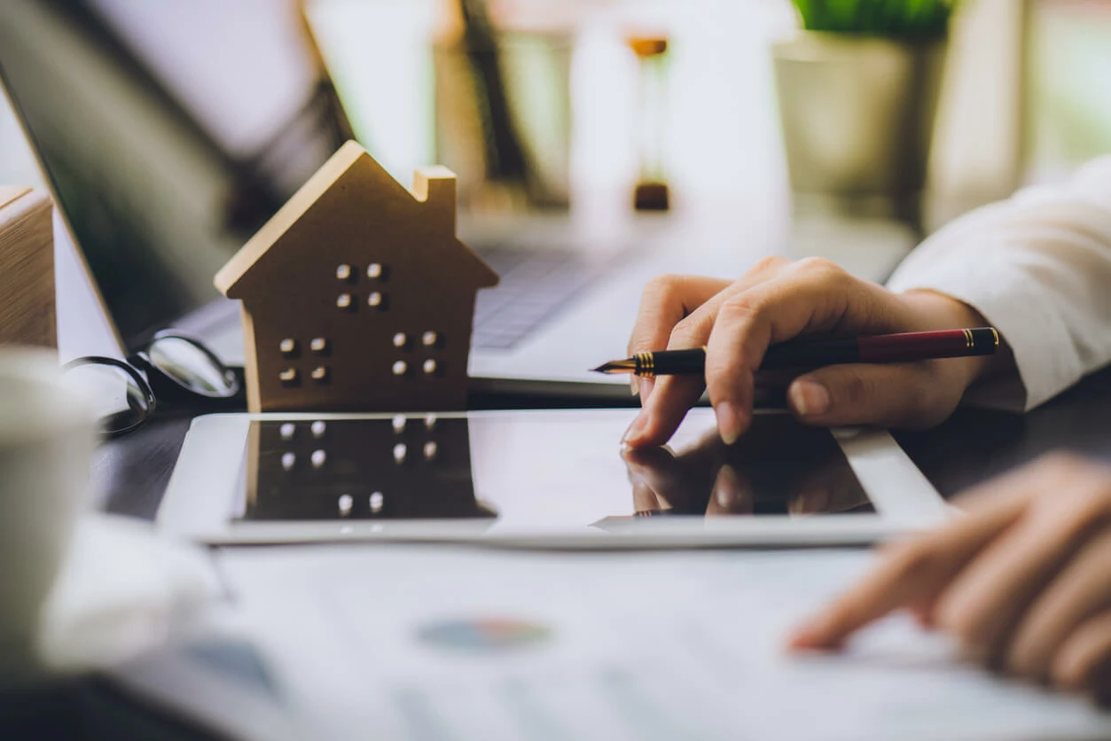 Femme manipulant une tablette à côté d'une maison en bois.