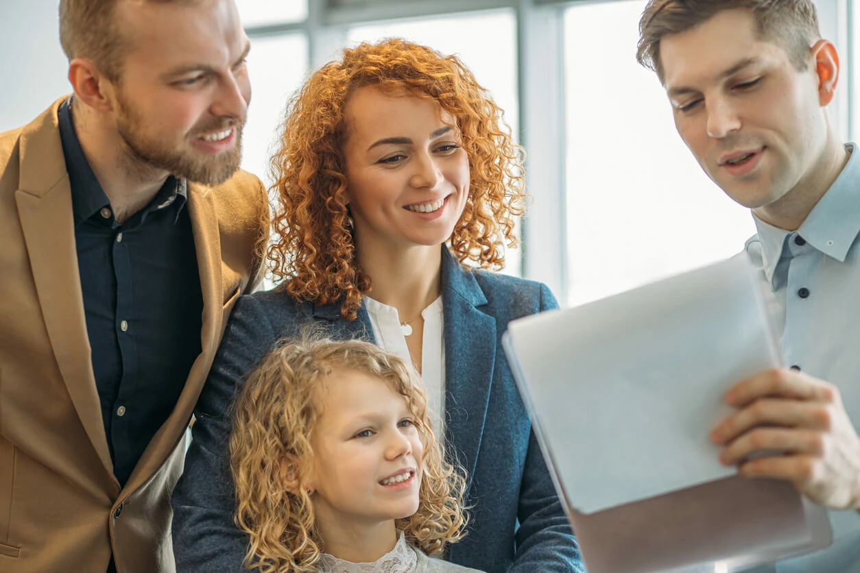 Un professionnel immobilier montrant un document à une famille de trois persones.
