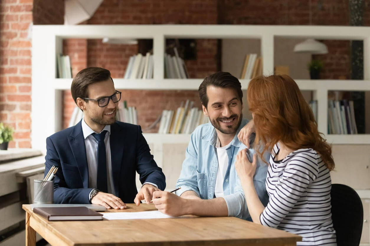 Professionnel immobilier devant un couple et des documents.