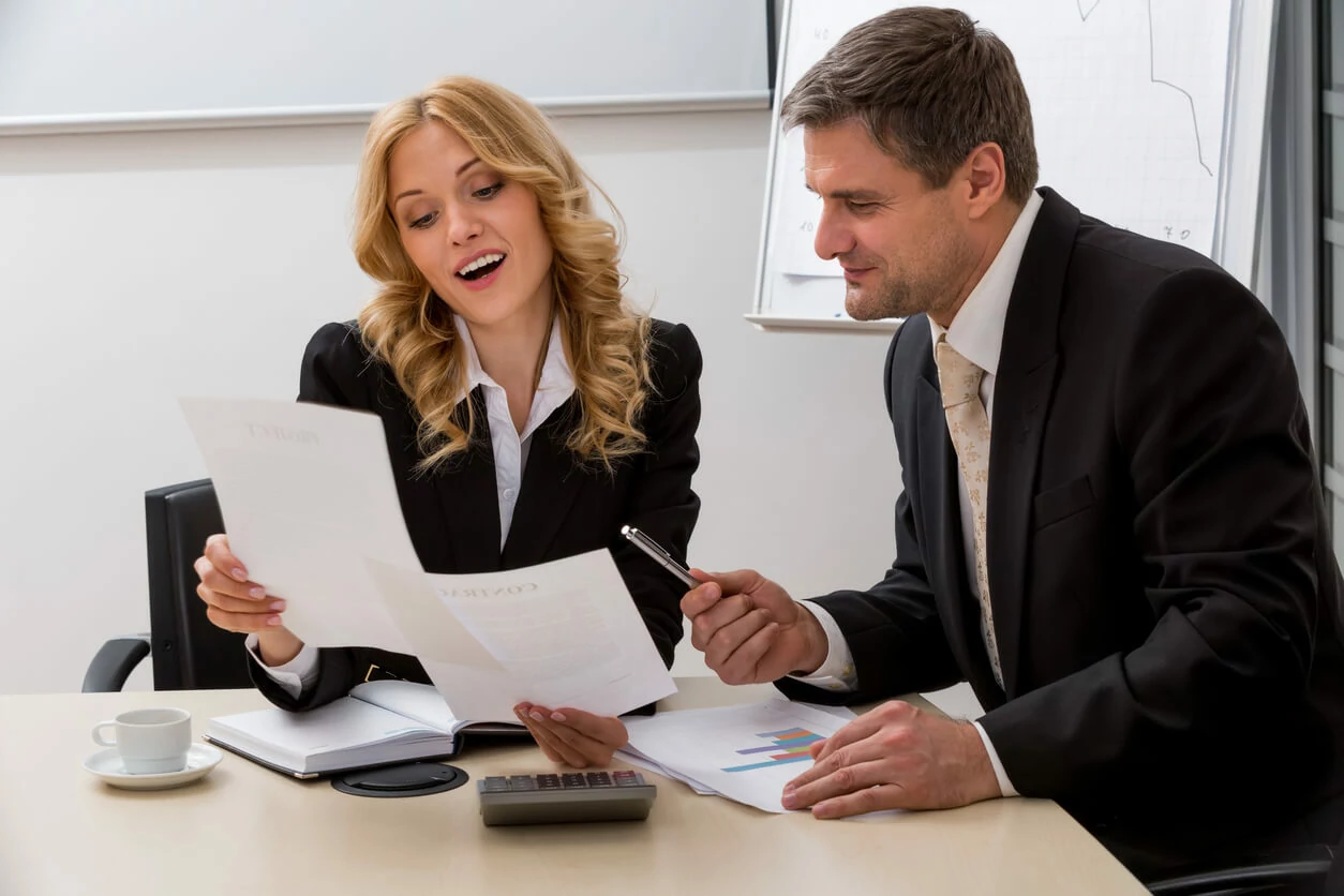 Un homme et une femme consultant des documents dans un bureau.